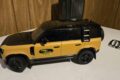Land Rover Defender 110 Trophy Edition 1:18 model in yellow with black roof, side view